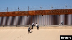 Asylum-seeking migrants walk out of the Rio Bravo River after crossing it to turn themselves in to U.S Border Patrol agents to request asylum in El Paso, Texas, as seen from Ciudad Juarez, Mexico, April 13, 2022. 