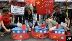 FILE - Filipino student activists set fire mock Chinese ships to protest recent island-building and alleged militarization by China off the disputed Spratlys group of islands in the South China Sea, in Manila, March 3, 2016. 