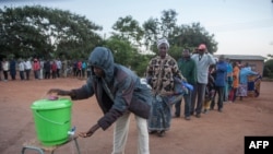 FILE - People queue to wash their hands to protect against the coronavirus before lining up to vote at a polling station, in Lilongwe, Malawi, June 23, 2020.