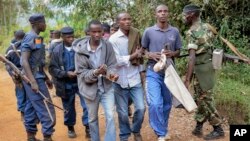 FILE - Three men walk in handcuffs after being arrested as organizers of an opposition demonstration, which was dispersed by police firing in the air, in Jenda, Burundi, June 12, 2015. 