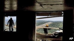 Backdropped by Israel's separation barrier, Palestinians work at a construction site in the West Bank Jewish settlement of Modiin Illit, March 14, 2011