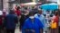 FILE - People wearing face masks walk through the busy Bara Taxi Rank in Soweto, South Africa, April 5, 2022. 