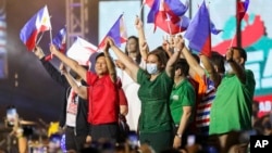 FILE - Former senator Ferdinand "Bongbong" Marcos Jr., center-left, and his running mate Davao City Mayor Sara Duterte, center-right, wave Philippine flags during rally announcing his presidential bid, at the Philippine Arena, Bulacan province, north of Manila.