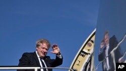 Britain's Prime Minister Boris Johnson waves as he boards a plane at Stansted Airport, northeast of London, April 20, 2022, for a visit to India. 