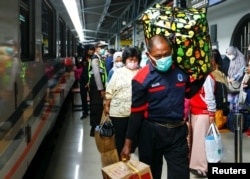 Penumpang membawa barang bawaan mereka saat mereka berjalan di stasiun kereta api untuk mudik, menjelang perayaan Idul Fitri, di tengah wabah COVID-19 di Jakarta, 5 Mei 2021. (REUTERS/Ajeng Dinar Ulfiana)