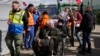 Volunteers help refugees in a wheelchair after fleeing the war from neighboring Ukraine at the border crossing in Medyka, southeastern Poland, April 11, 2022.