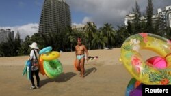 FILE - Vendors selling swimming accessories walk on Sanya Bay beach in Sanya, Hainan province, China November 26, 2020. (REUTERS/Tingshu Wang/File Photo)