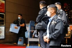 FILE - A police officer collects a box of evidence after a search at the office of Stand News, in Hong Kong, China, Dec. 29, 2021.