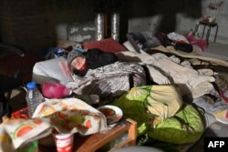 An elderly woman sleeps on the floor as residents of a building, partially destroyed after shelling, live in its basement on the northern outskirts of Kharkiv, Ukraine, April 5, 2022.