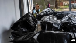 A woman looks at black bags containing bodies of dead civilians, while she waits for her son's body to be delivered to the morgue so that she can give him a decent burial, in the cemetery of Mykulychi, near Kyiv, Ukraine, April 16, 2022. 