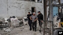 Security force members aid an injured man following a Russian bombing of a factory in Kramatorsk, in eastern Ukraine, on April 19, 2022. 