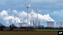 FILE - Renewable and fossil-fuel energy is produced when wind generators are seen in front of a coal-fired power plant near Jackerath, Germany, Dec. 7, 2018. 