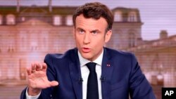 FILE - French President and centrist candidate for reelection Emmanuel Macron gestures during a news broadcast of French TV channel TF1, outside Paris, April 13, 2022.