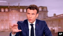FILE - French President Emmanuel Macron gestures during a news broadcast of French TV channel TF1, outside Paris, April 13, 2022. 