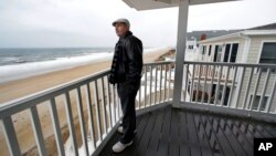 Real estate agent Tom Saab stands on a oceanfront deck at a condo he developed in Salisbury, Mass., Feb. 15, 2019. Academic researchers say concerns over rising sea levels and increased flooding are having subtle but significant impacts on coastal property values.