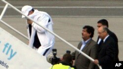 FILE - Lockerbie airline bomber Abdel Basset al-Megrahi, left, who was released from prison on compassionate grounds because he was terminally ill, boards an airplane accompanied by Libyan officials at Glasgow airport, Glasgow, Scotland, Aug. 20, 2009.