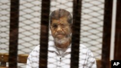 FILE - In this May 8, 2014 file photo, Mohammed Morsi sits in a defendant cage in the Police Academy courthouse in Cairo, Egypt.(AP Photo/Tarek el-Gabbas, File) 