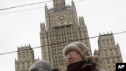 A demonstrator holds a Syrian national flag with a portrait of Syrian President Assad during a rally in support of Syria in front of the Russian Foreign Ministry in Moscow, Feb. 16, 2012.