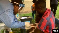Seorang petugas kesehatan memberikan vaksin ebola di distrik Kasese, Uganda, Minggu (16/6). (Foto: H. Athumani/VOA)