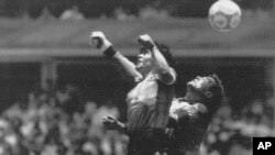 L'argentin Diego Maradona, à gauche, bat le gardien anglais Peter Shilton et inscrit son premier de deux buts en match de quart de finale de la Coupe du monde à Mexico ; un but controversé qualifié de la «Main de Dieu» et marqué du son poing gauche, à Mex