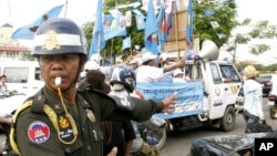 A Cambodian military police officer, left, traffics during the election campaign in Phnom Penh, file photo. 