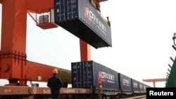 资料照：中国浙江省义乌火车站的一名工人在给开往欧洲的火车上装载集装箱。（2017年4月15日）