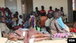 A young South Sudanese refugee girl shields her face from the scorching sun as she waits in line at Maaji Health Center, Adjumani district, northern Uganda, June 14, 2017. (H. Athumani/VOA)