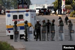 An ambulance carrying wounded indigenous people passes next to Venezuelan National guards on its way back to Venezuela, at the border between Venezuela and Brazil, in Pacaraima, Roraima state, Brazil, Feb. 22, 2019.