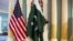 A State Department employee adjusts a Pakistani national flag before a meeting of U.S. and Pakistani officials at the State Department in Washington, Feb. 19, 2015. A U.S. Defense Department delegation is traveling to Pakistan for talks next week. 