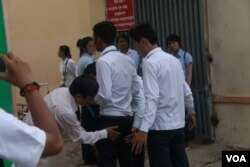 អនុរក្សកំពុងពិនិត្យ​មើល​សំណៅ​ឯកសារ​នៅ​លើ​ខ្លួន​បេក្ខ​ជនប្រលង​មធ្យម​សិក្សា​ទុតិយភូមិ នៅ​ថ្ងៃ​ទី​២៤​ ខែ​សីហា​ ឆ្នាំ២០១៥​ នៅ​មណ្ឌល​ប្រលងសាលាបឋម​សិក្សារ​ចតុមុខ​។ (ស៊ូ​ ពិសែន/VOA)