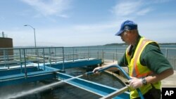 FILE - Robert Newman hoses off a portion of sewage treatment Plant No. 2 in Coos Bay, Oregon, May 13, 2010.