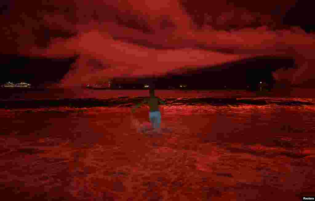 2018年1月1日在巴西里约热内卢举行的新年庆祝活动中，科帕卡巴纳海滩烟花怒放，映红天空和海面，一名男子跑入海里。