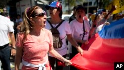 A protester chants: "elections now!" as she holds on to the edge of a national flag, during a protest in Caracas, Venezuela, Jan. 23, 2017. AP Photo/Ariana Cubillos)