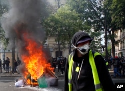 A man walks past garbage that was set on fire in Paris, May 1, 2019. Brief scuffles between police and protesters broke out in Paris as thousands of people gathered for May Day rallies under tight security measures.