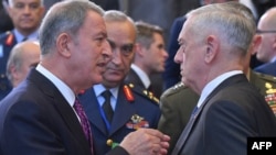 FILE - Turkish Defense Minister Hulusi Akar, left, speaks with U.S. Defense Secretary Jim Mattis prior to a defense ministerial meeting at NATO headquarters in Brussels, Oct. 4, 2018.