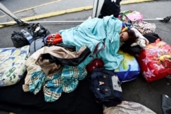 FILE - A Venezuelan migrant rests outside the Ecuadorean migrations office at the Rumichaca International Bridge, in the border between Tulcan, Ecuador, and Ipiales, Colombia on August 20, 2018.