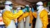 Guinea's health workers wearing protective suits join members of the Medecins sans frontieres Ebola treatement center near the main Donka hospital in Conakry on Sept. 25, 2014. 