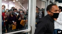 Sekelompok orang yang menentang proses penghitungan suara pada pemilu AS (kiri) menunggu di luar setelah petugas pemilu (kanan) menutup pintu ke ruang penghitungan suara di Detroit, Rabu, 4 November 2020. 