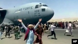 Hundreds of people run alongside a U.S. Air Force C-17 transport plane as it moves down a runway of the international airport, in Kabul, Afghanistan, Monday, Aug.16. 2021. (Verified UGC via AP)
