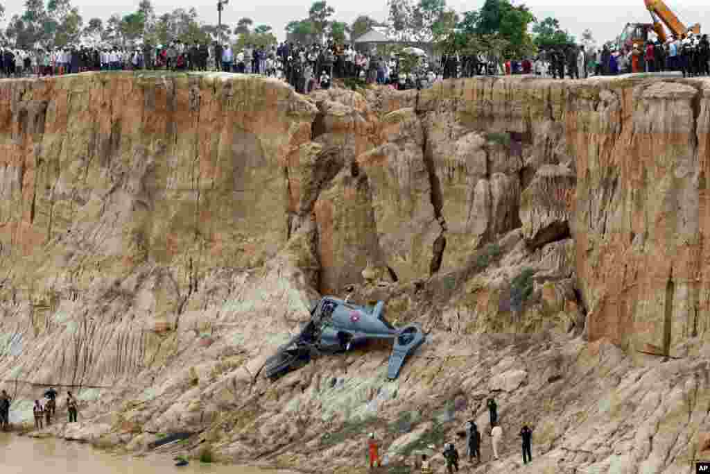 Soldiers use a crane to lift an aft section of a helicopter retrieved from a pond following its crash in Prey Sar village at the outskirt of Phnom Penh, Cambodia.