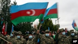 FILE - Azerbaijani soldiers wave national flags after the transfer of the Lachin region to Azerbaijani control, part of a peace deal requiring Armenia to cede Azerbaijani territories it held outside Nagorno-Karabakh, Dec. 1, 2020.