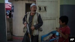 Seorang anak laki-laki melihat senapan penjaga dari minoritas Syiah Hazara di luar sebuah masjid di Kabul, 10 November 2021. (Foto: AP)