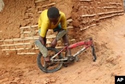 A young boy inspects part of a bicycle retrieved from a site where two houses were crushed by the collapse of a massive, sprawling dumpsite in Pemba city on the northeastern coast of Mozambique, Monday, April, 29, 2019.