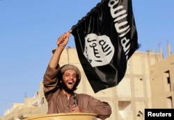 A militant Islamist fighter waving a flag, cheers as he takes part in a military parade along the streets of Syria's northern Raqqa province June 30, 2014. The fighters held the parade to celebrate their declaration of an Islamic "caliphate" after the gro