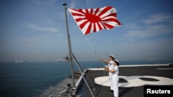 Sailors raise the Japanese naval ensign on the deck of Japanese helicopter carrier Kaga before its departure for naval drills in the Indian Ocean, near Jakarta Port, Indonesia September 22, 2018. (REUTERS/Kim Kyung-Hoon)