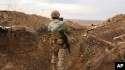 Ukrajinski vojnik drži mačku dok hoda kroz rov na liniji razdvajanja od proruskih pobunjenika u blizini Debaltseva, region Donjetska, Ukrajina, 3. decembra 2021.
