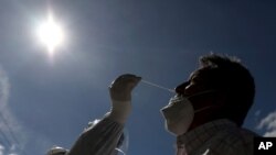 A healthcare worker collects a nasal swab sample to test for COVID-19, in Bogota, Colombia, Jan. 27, 2021. 