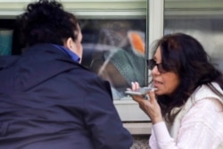 Two sisters talk on a phone as they visit through a window with their 76-year-old mother, who has tested positive for the new coronavirus, March 12, 2020, in Kirkland, Wash.