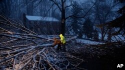 Streets department workers David Boardly, left, and James Ockimey clear a downed tree during a winter storm, March 2, 2018, in Marple Township, Pa. A nor'easter pounded the Atlantic coast with hurricane-force winds and sideways rain and snow Friday.