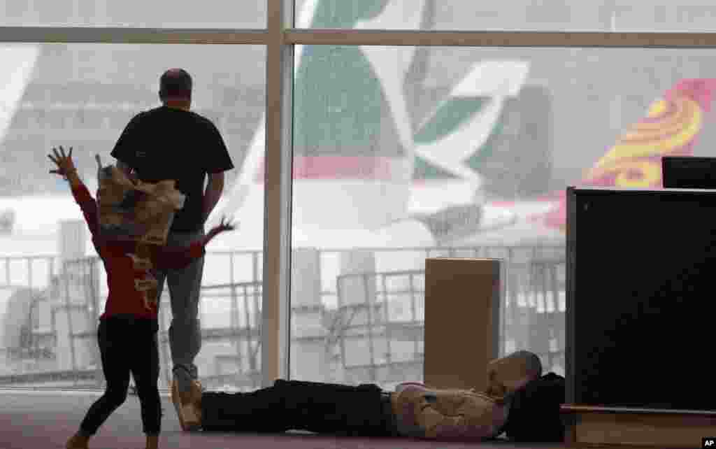 A girl dances with a newspaper to entertain herself after a night stranded at the airport by Typhoon Vicente in Hong Kong, July 24, 2012.